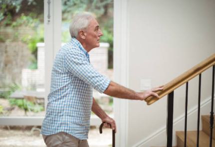 homme âgé avec une cane devant un escalier intérieur